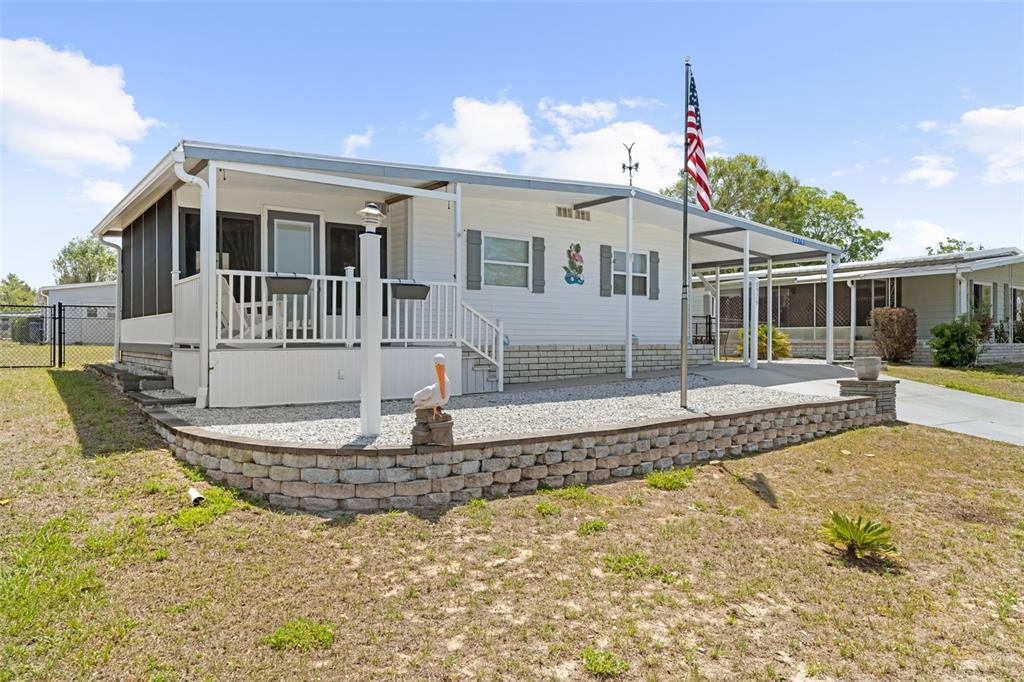 A single-story manufactured home features a front porch, a gravel yard, and an American flag — 8979 HIGHPOINT BOULEVARD, BROOKSVILLE, FL