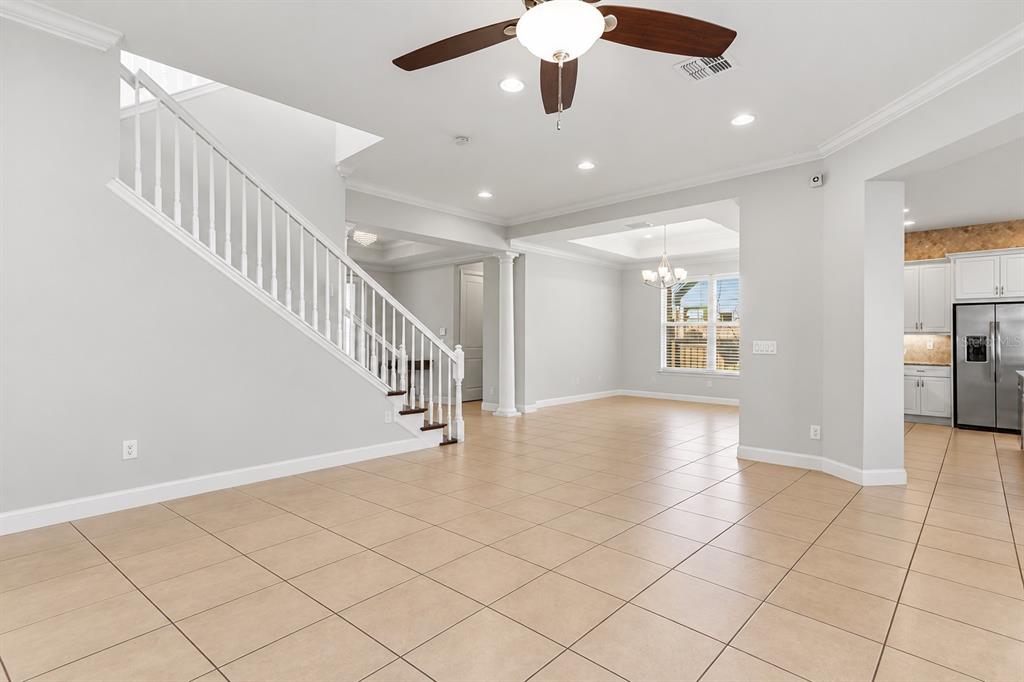 A covered porch features brick pavers, two dark wicker chairs, and a bright red double door — 12837 BOVET AVENUE, ORLANDO, FL