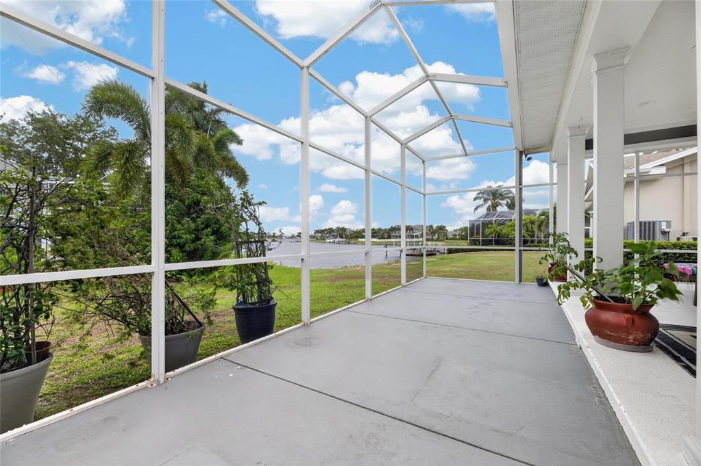 A screened-in patio with a concrete floor overlooks a grassy lawn and a canal — 435 MANNS HARBOR DRIVE, APOLLO BEACH, FL