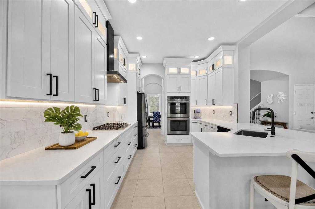 A modern white kitchen features quartz countertops, stainless steel appliances, and a central island — 435 MANNS HARBOR DRIVE, APOLLO BEACH, FL