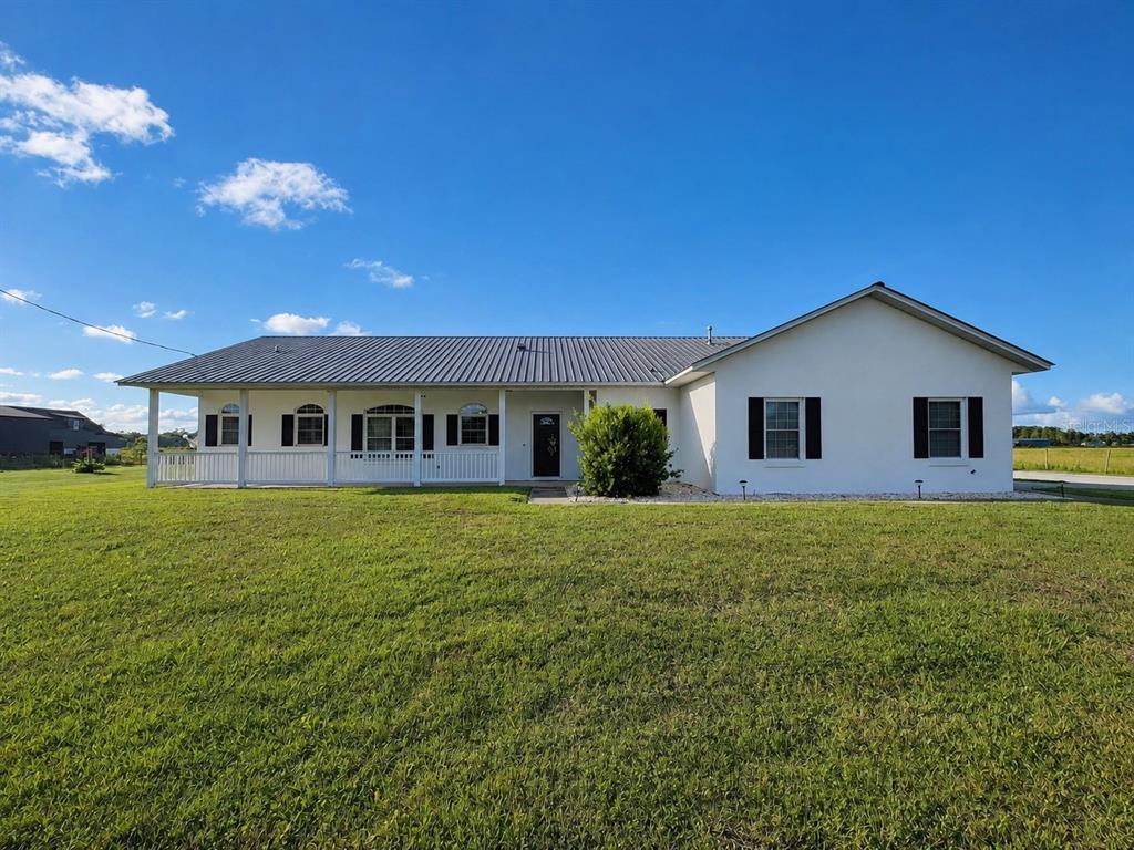 A single-story house with a metal roof, a covered porch, and a large front lawn — 9120 COUNTY ROAD 304, BUNNELL, FL