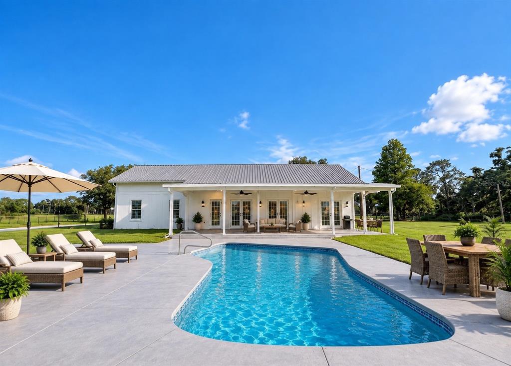 A covered patio overlooks a swimming pool and a large yard with several outbuildings — 9120 COUNTY ROAD 304, BUNNELL, FL