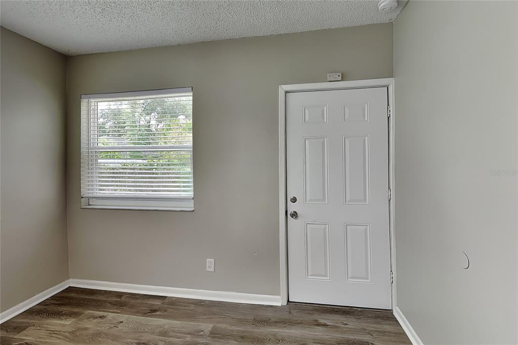 A room with light gray walls, a white six-panel door, and wood-look flooring — 1404 FERNWOOD PLACE, SEFFNER, FL