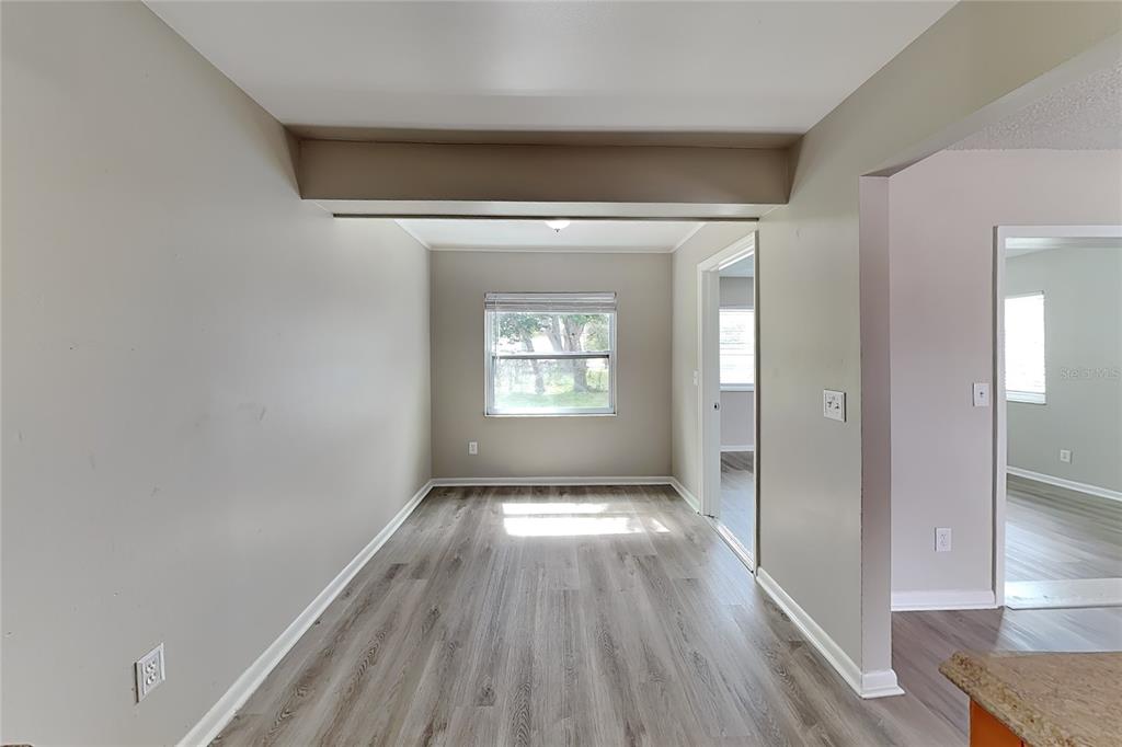 A dining area with light gray walls, wood-look flooring, and a window overlooking the yard — 1404 FERNWOOD PLACE, SEFFNER, FL