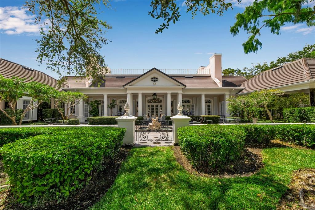 A symmetrical one-story house with a columned portico, tiled roof, and manicured hedges — 101 OSPREY POINT DRIVE, OSPREY, FL