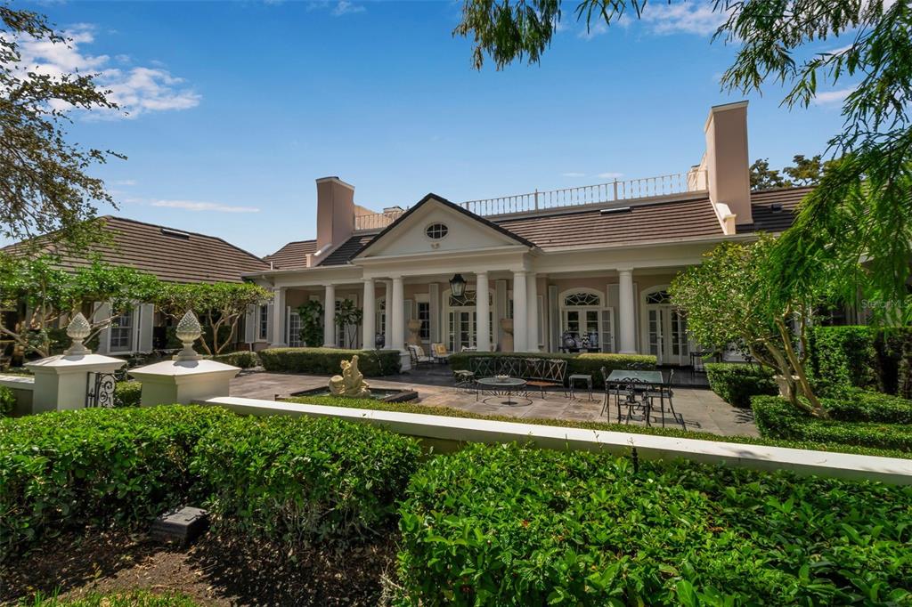 A rear view of a house with a patio, columns, and manicured hedges — 101 OSPREY POINT DRIVE, OSPREY, FL