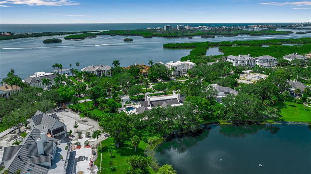 An aerial view shows luxury waterfront homes surrounded by lush trees and a small lake — 101 OSPREY POINT DRIVE, OSPREY, FL