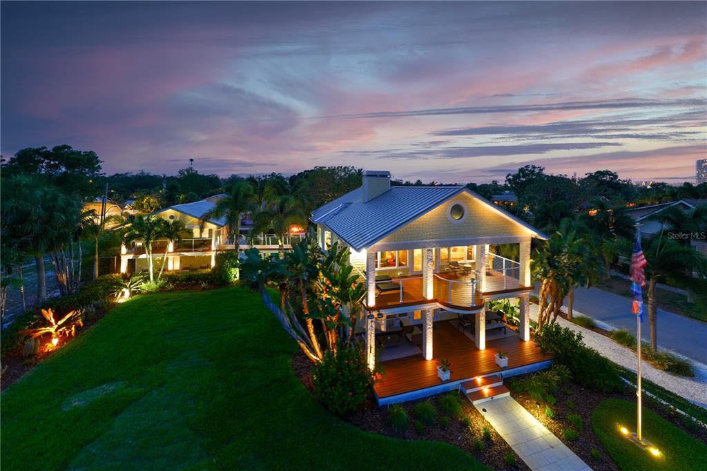 A two-story yellow house with a covered porch sits behind a stone retaining wall — 1803 BEACH DRIVE SE, ST PETERSBURG, FL
