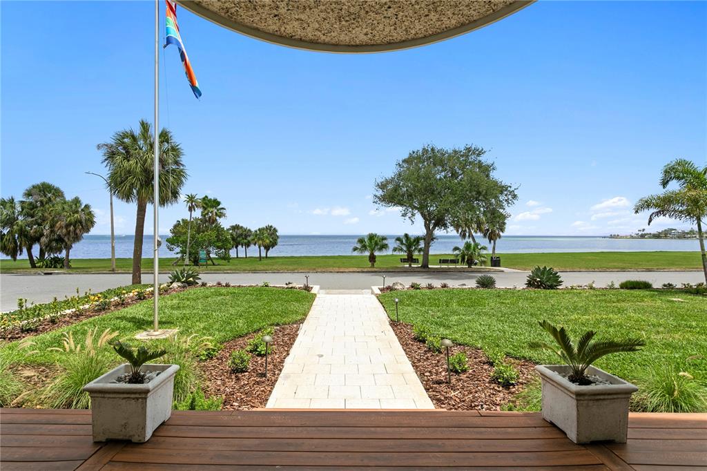 An aerial view shows a coastal property with a yellow house, lush landscaping, and ocean views — 1803 BEACH DRIVE SE, ST PETERSBURG, FL