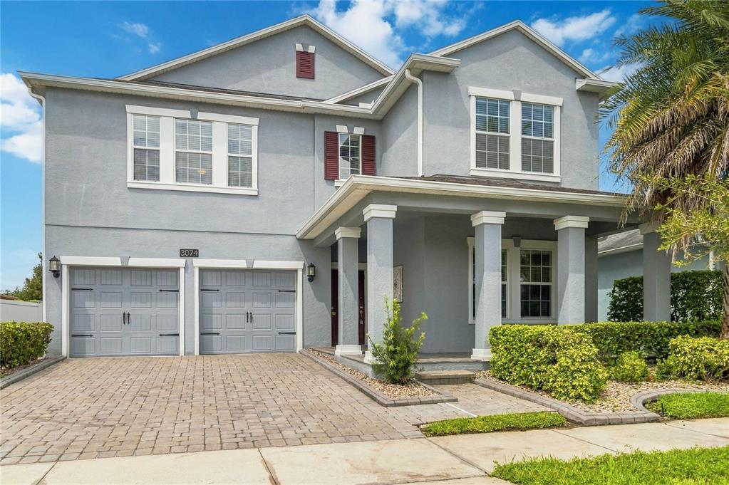 A two-story gray house with a two-car garage, front porch, and paved driveway — 3074 WHITE HORSE COURT, KISSIMMEE, FL