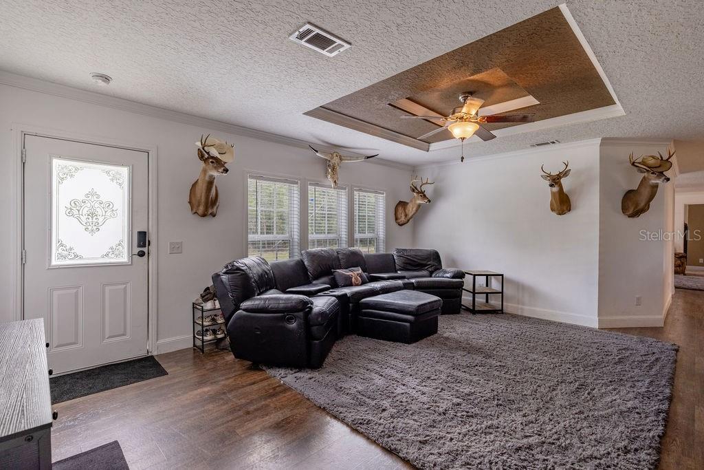 A single-story manufactured home with tan siding sits on a large, grassy lot — 24821 OLD DEER ROAD, PAISLEY, FL