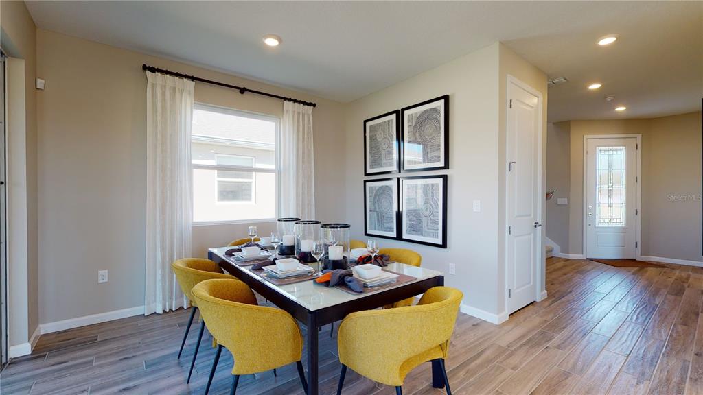 A dining room features a table with yellow chairs, framed wall art, and wood flooring — 5311 SPRING MAIDEN CIRCLE, APOLLO BEACH, FL