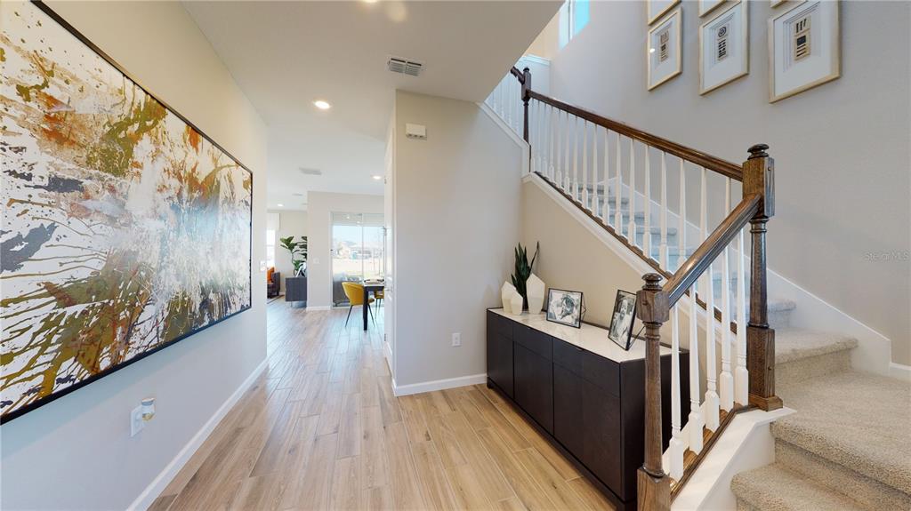 An entryway features wood-look tile flooring, a staircase with a wooden railing, and wall art — 5311 SPRING MAIDEN CIRCLE, APOLLO BEACH, FL