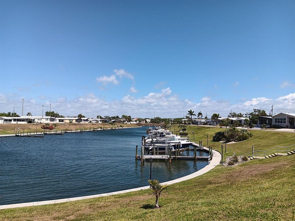 A canal with docked boats is bordered by a grassy lawn and residential mobile homes — 811 BOGIE, VENICE, FL