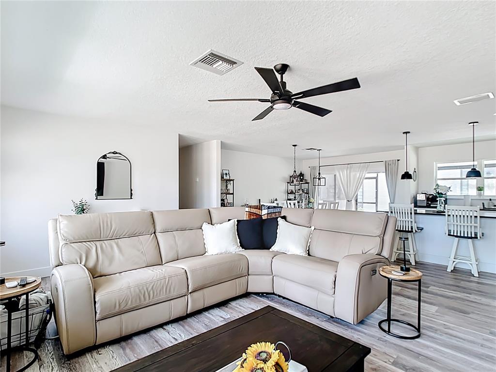 A gray metal workshop and a tan house sit on a wooded, dirt-covered lot — 7374 CIRCLE DRIVE, LADY LAKE, FL