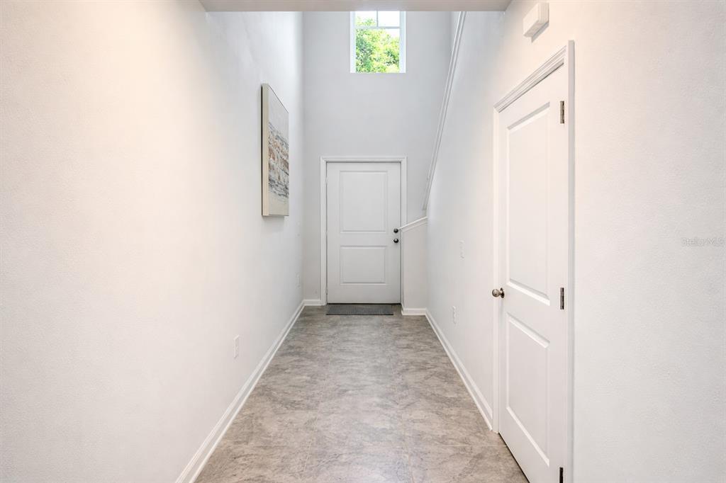 A bright entryway features a high ceiling, a front door, and light-colored tile flooring — 1824 FOREMAN RD, EAGLE LAKE, FL