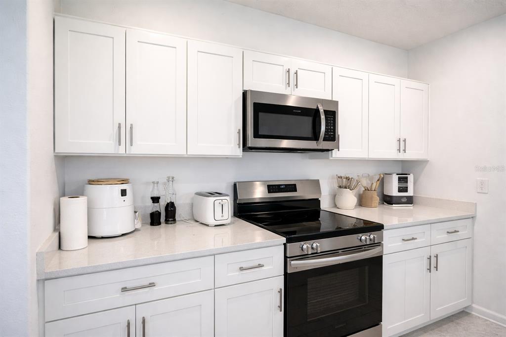 A kitchen features white cabinets, stainless steel appliances, and light-colored countertops — 1824 FOREMAN RD, EAGLE LAKE, FL