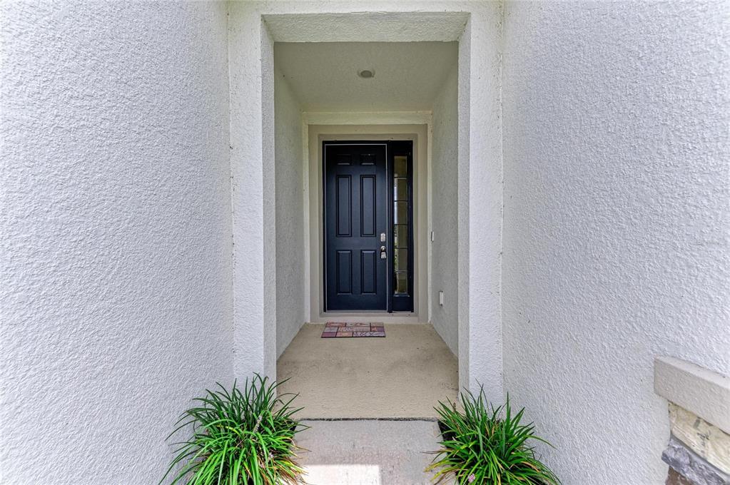A dark front door with a side window is set within a recessed entryway — 12432 DORA TRAIL, PARRISH, FL