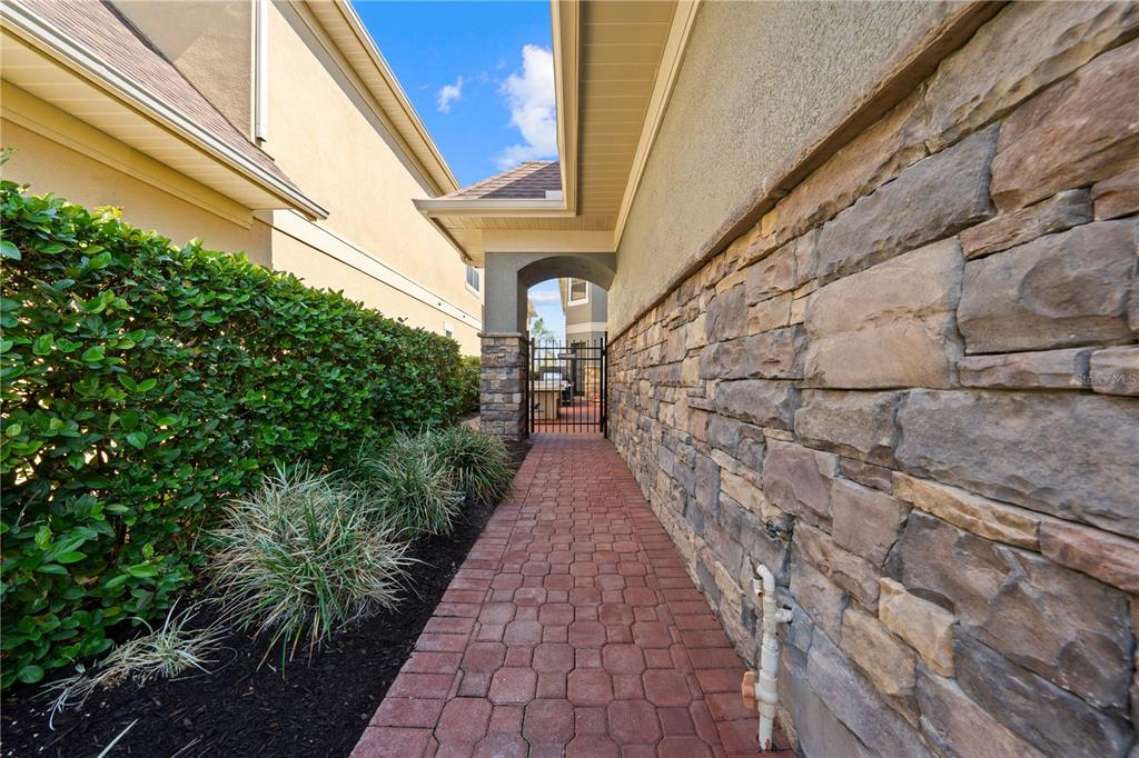 A stone-walled walkway leads to a gated entrance between two residential buildings — 785 GOLDEN BEAR DRIVE, REUNION, FL