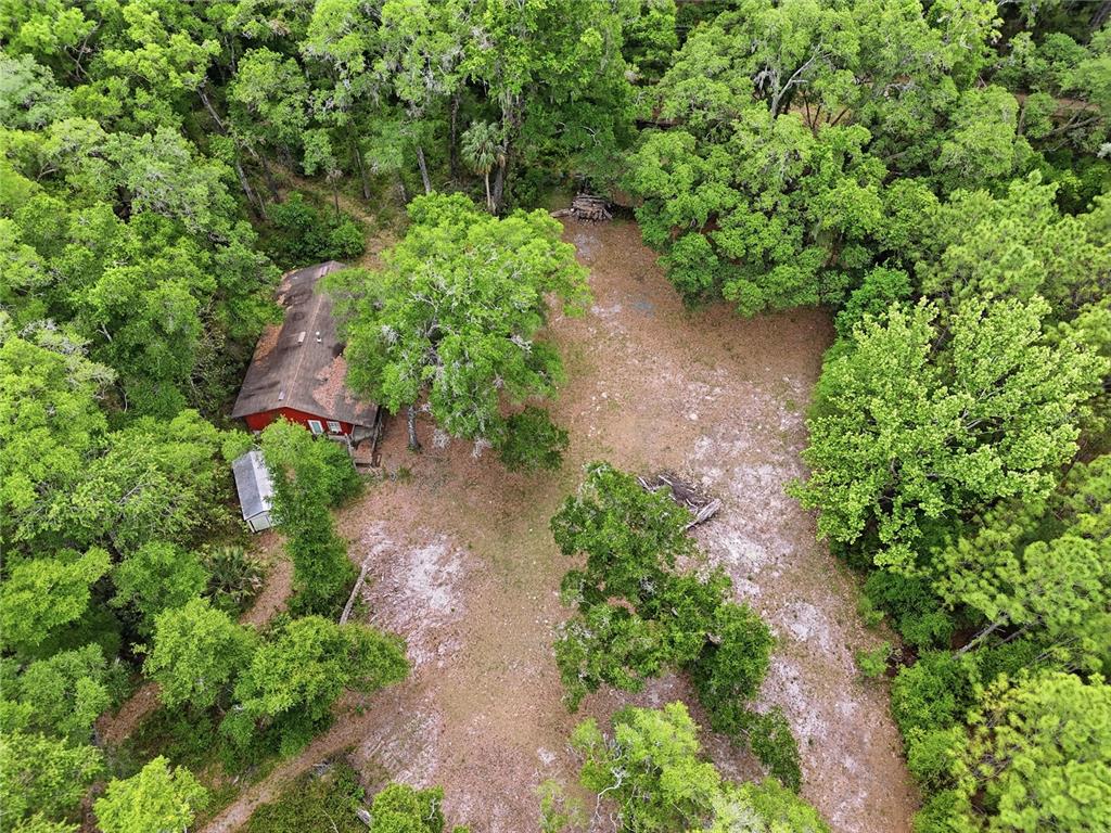 An aerial view shows a red house situated on a wooded lot with cleared land — 8009 SW 131ST TERRACE, ARCHER, FL
