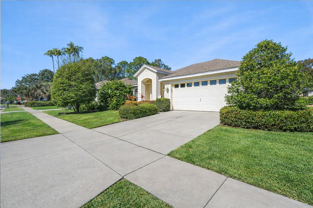 A single-story house with a beige exterior, a two-car garage, and a manicured front lawn — 8032 PINE HOLLOW DRIVE, MOUNT DORA, FL