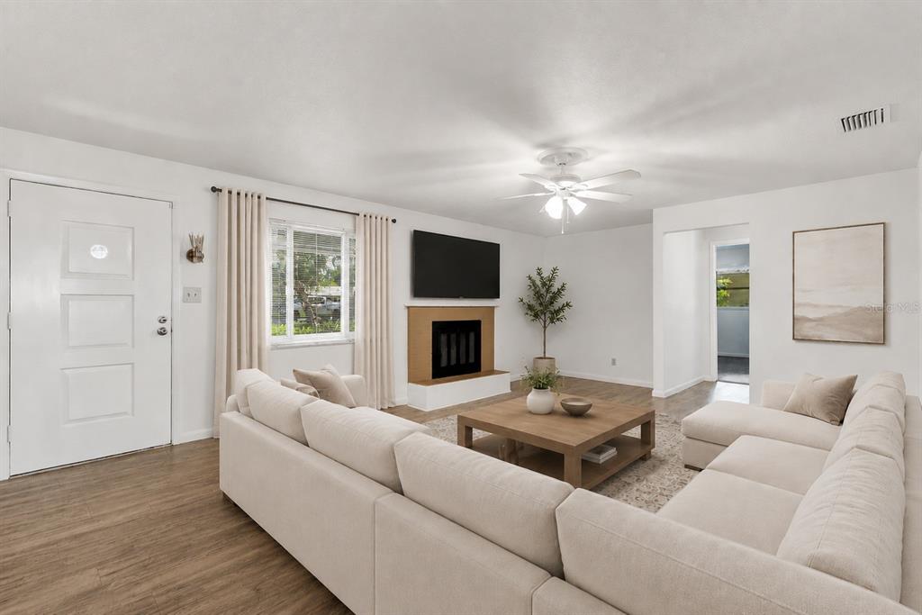 A living room features a white sectional sofa, a fireplace with a television, and wood flooring — 1503 MOSS AVENUE, LEESBURG, FL