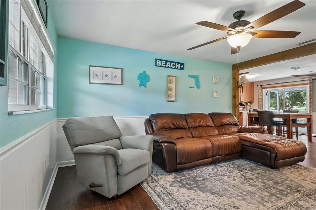A living room features a brown leather sectional, a gray recliner, and light blue walls — 8904 CLAYTON LANE, LAKELAND, FL