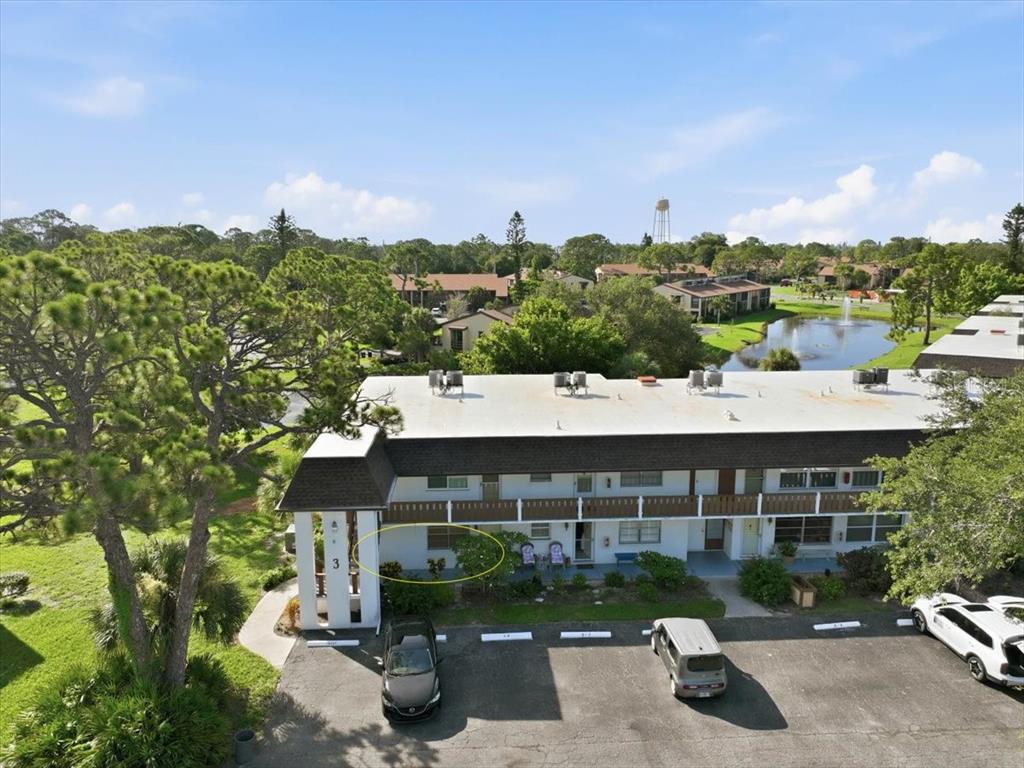 An aerial view of a multi-story apartment building with a parking lot and pond nearby — 3 QUAILS RUN BOULEVARD UNIT 3105, ENGLEWOOD, FL
