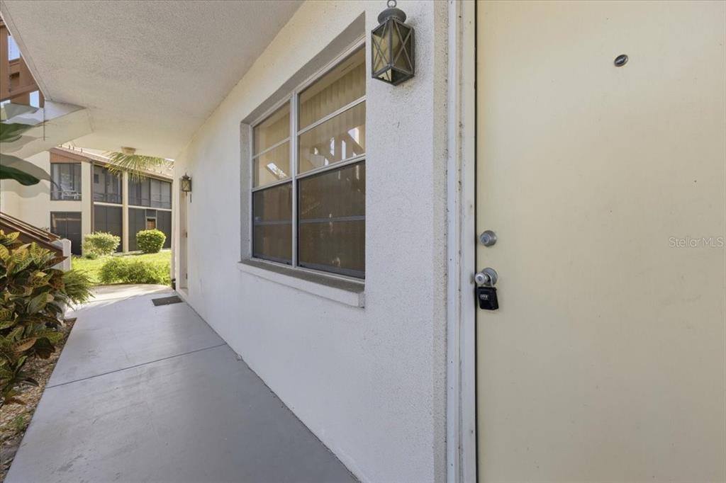 An empty room features beige tile flooring, a white front door, and a ceiling fan — 3 QUAILS RUN BOULEVARD UNIT 3105, ENGLEWOOD, FL