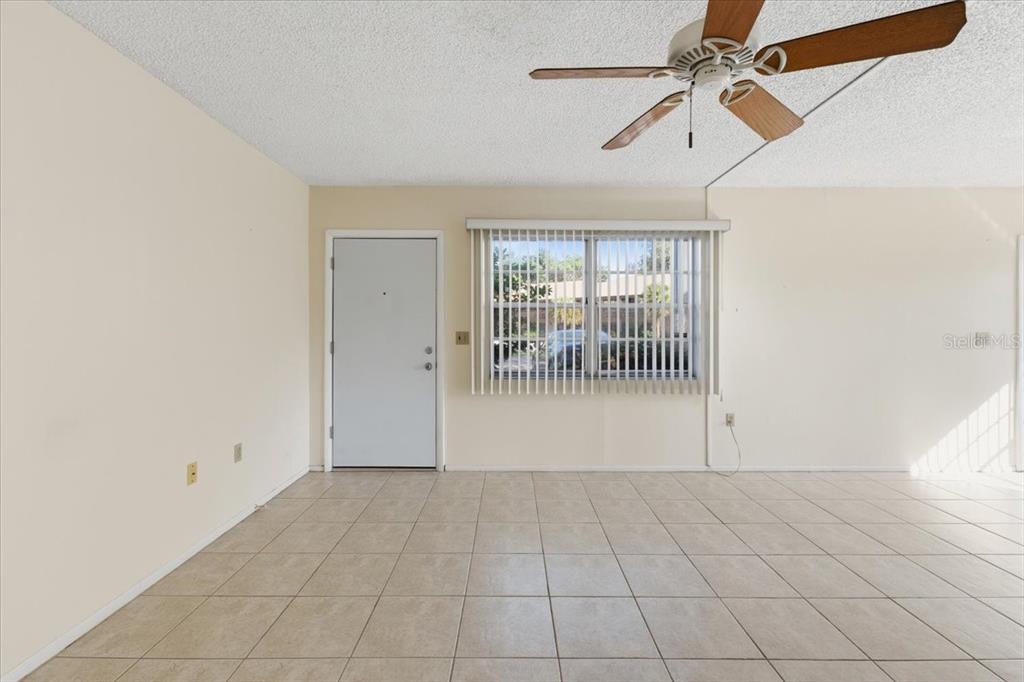 This living room features a sectional sofa, a television, and a ceiling fan — 3 QUAILS RUN BOULEVARD UNIT 3105, ENGLEWOOD, FL