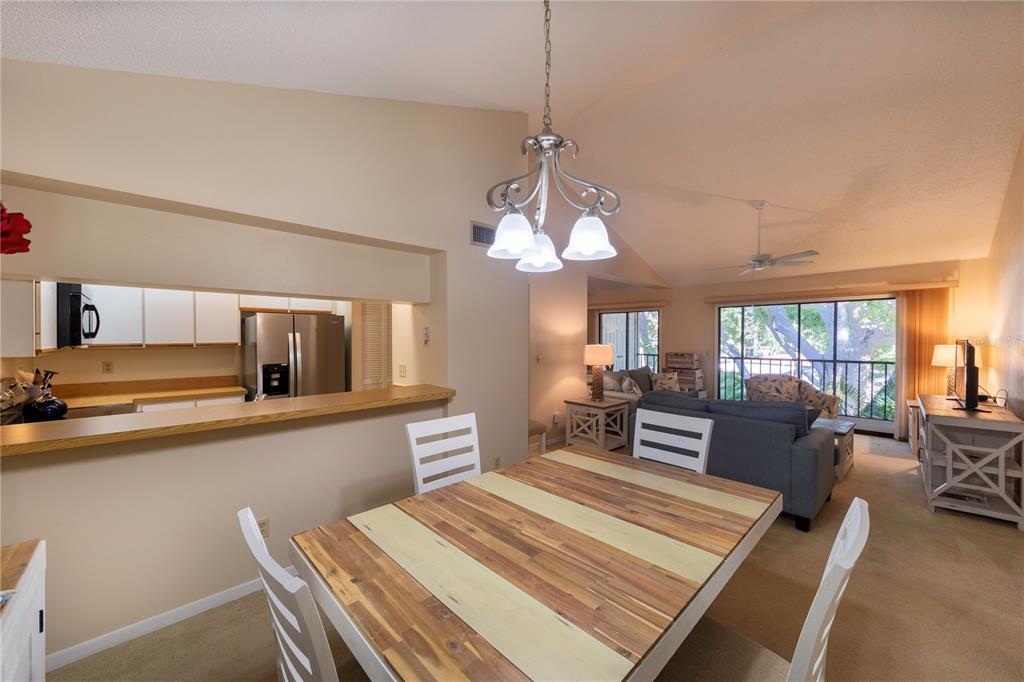 A dining area with a wood-topped table overlooks a living room and kitchen — 646 BIRD BAY DRIVE E UNIT 207, VENICE, FL