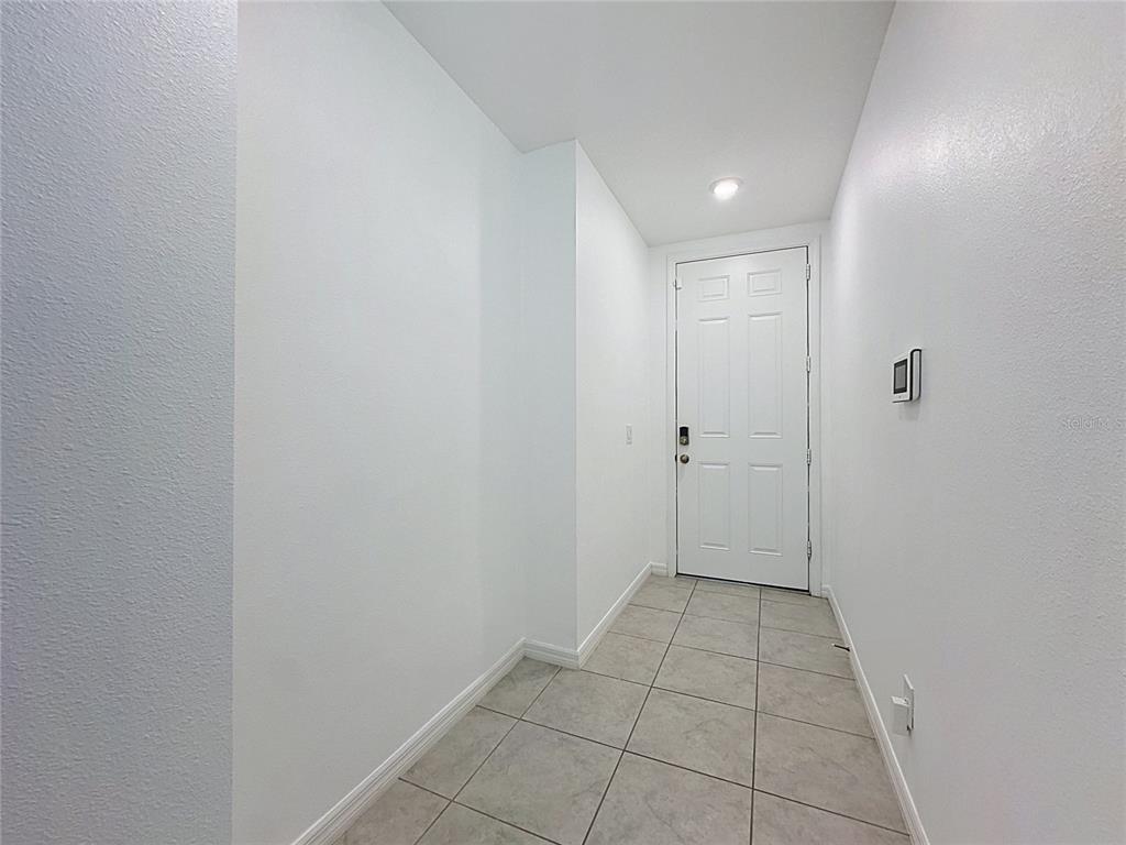 A small entryway with white walls, tile flooring, and a white front door — 3442 MONACO LN, DAVENPORT, FL