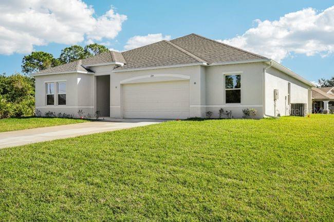 A single-story house with a light-colored exterior, a two-car garage, and a large front lawn — 16492 CRANE ROAD, WEEKI WACHEE, FL