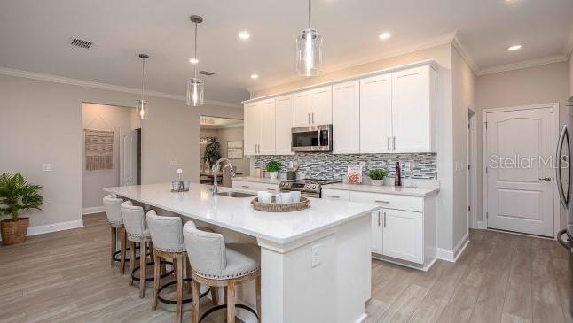 A modern kitchen features white cabinets, a large island with bar seating, and light flooring — 16492 CRANE ROAD, WEEKI WACHEE, FL