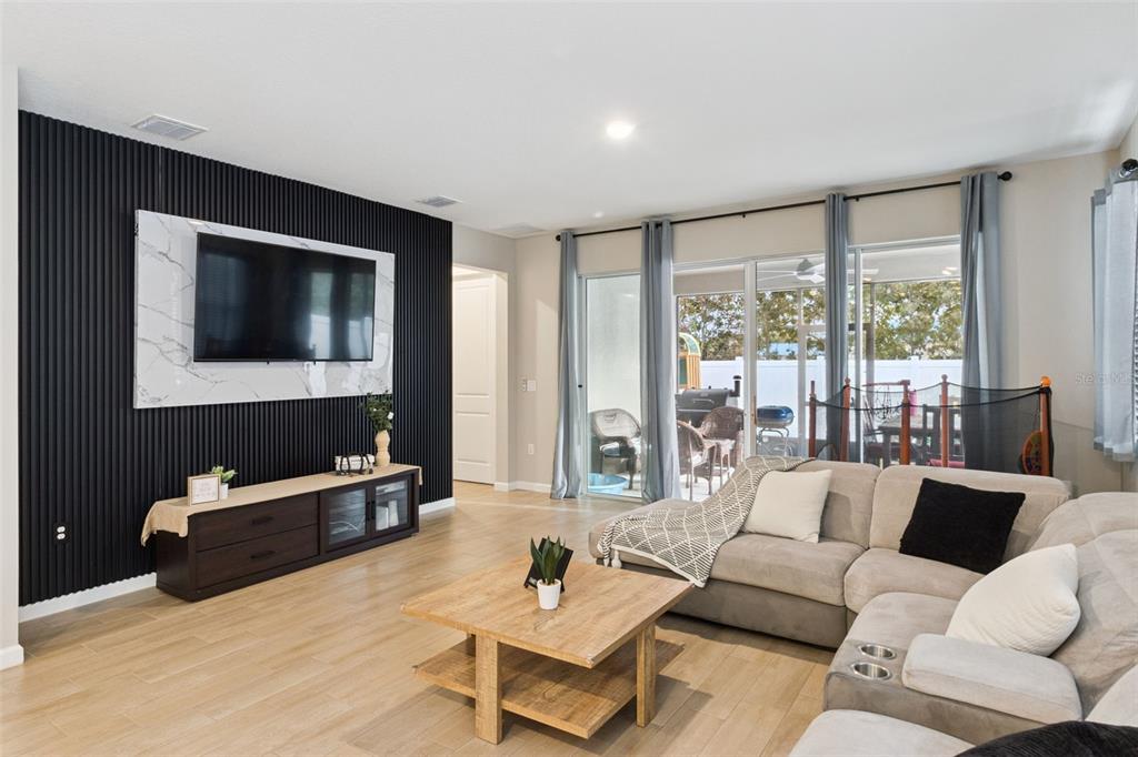 A living room features a black slatted accent wall, a television, and a sectional sofa — 2849 CATHY BOULEVARD, WINTER HAVEN, FL