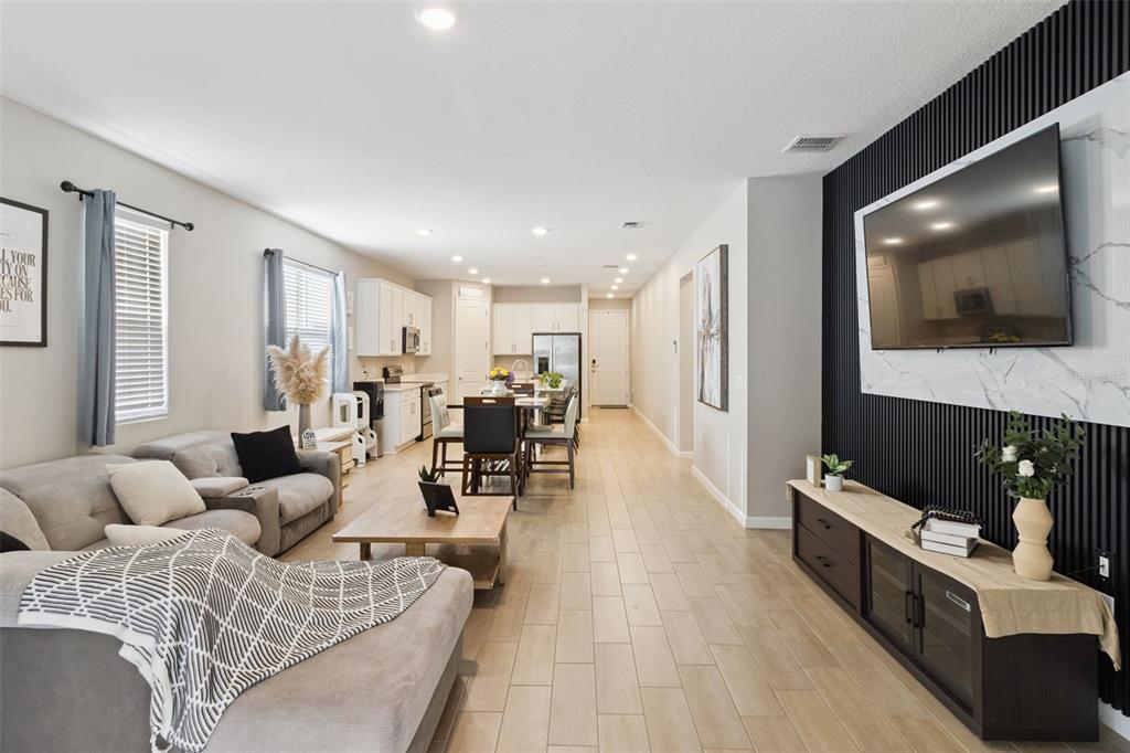 An open-concept living room and kitchen featuring light wood-look tile flooring and a slatted wall — 2849 CATHY BOULEVARD, WINTER HAVEN, FL