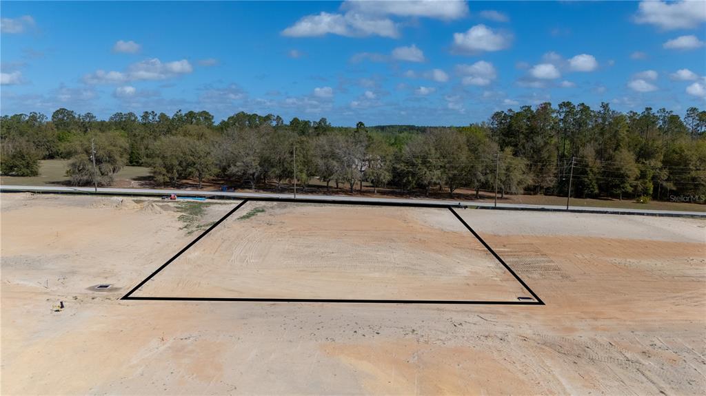 An aerial view shows a cleared, rectangular plot of land outlined in black — 32880 DUNNE ROAD, SAN ANTONIO, FL
