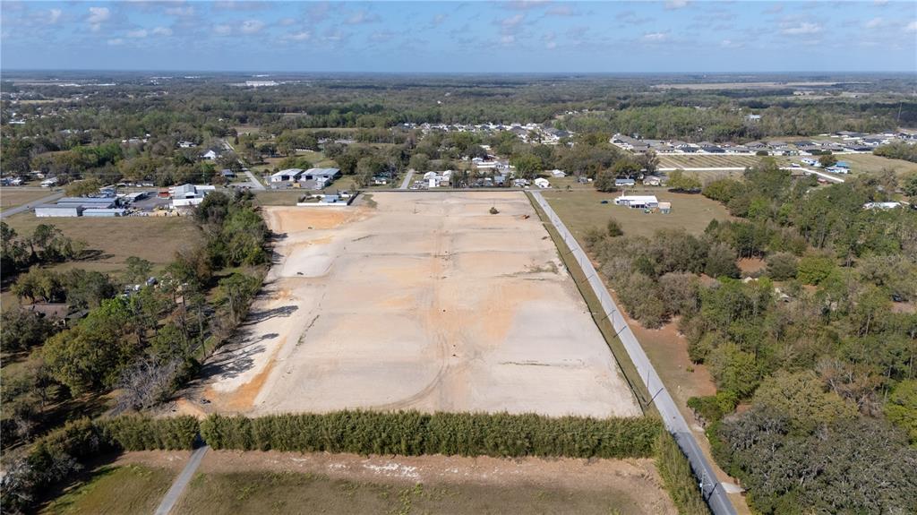 An aerial view shows a large, cleared rectangular lot bordered by trees and a road — 32880 DUNNE ROAD, SAN ANTONIO, FL