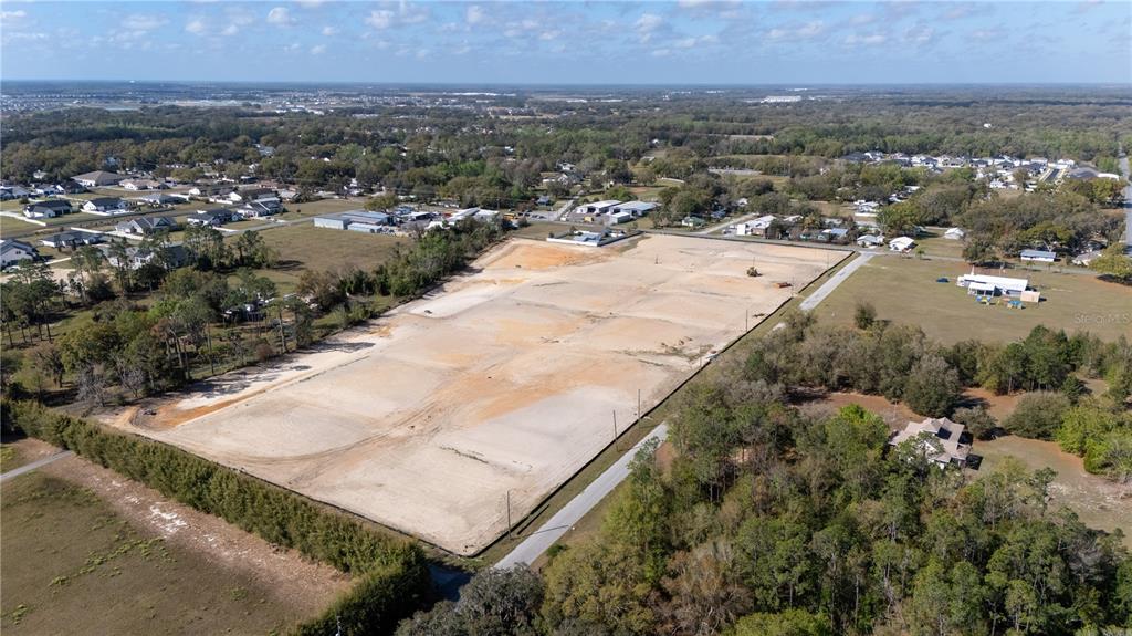 An aerial view shows a large, cleared rectangular plot of land surrounded by trees and houses — 32880 DUNNE ROAD, SAN ANTONIO, FL