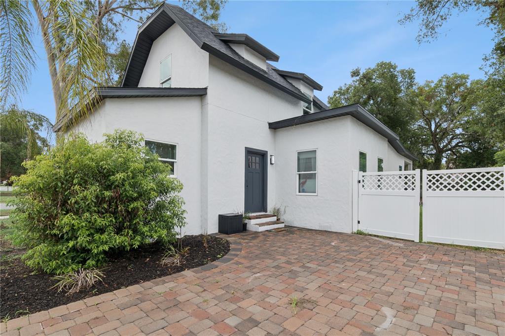 A white two-story house with a dark door and a brick paver driveway — 732 E ORANGE AVENUE, EUSTIS, FL