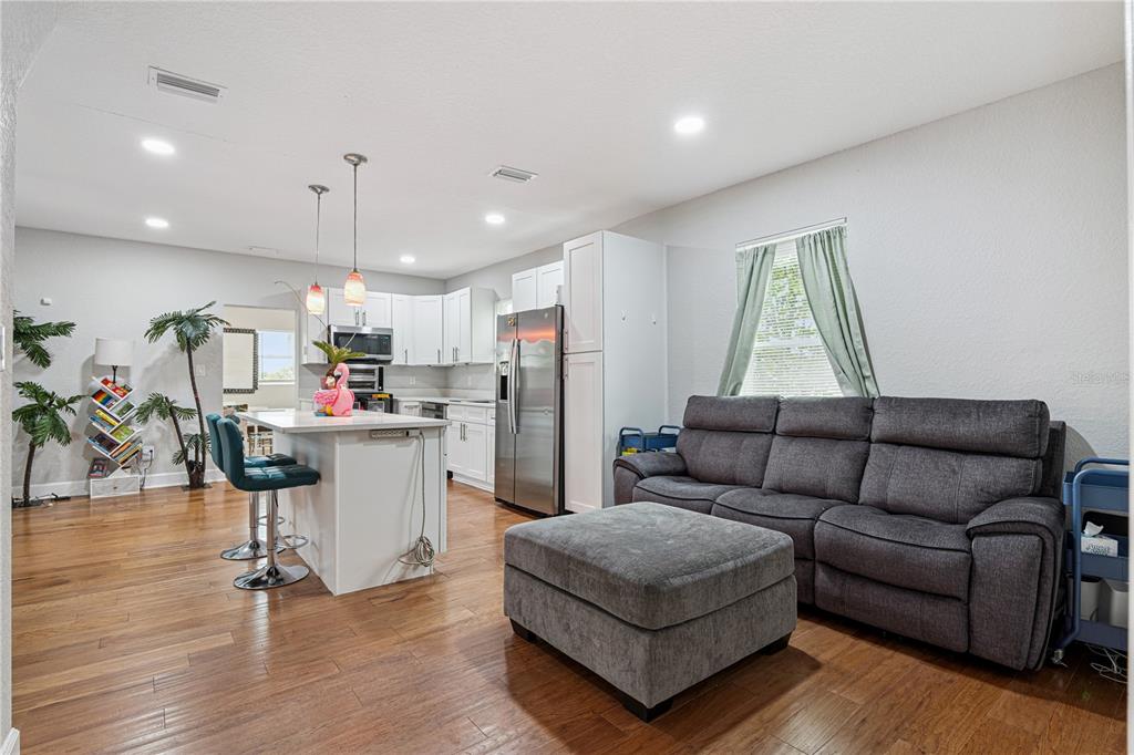 A kitchen with white cabinets and a gray sofa with an ottoman in the foreground — 732 E ORANGE AVENUE, EUSTIS, FL