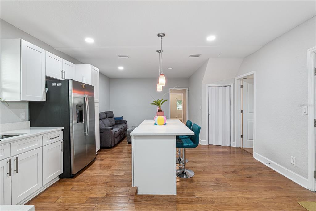 A kitchen with white cabinets, a stainless steel refrigerator, and a central island with seating — 732 E ORANGE AVENUE, EUSTIS, FL