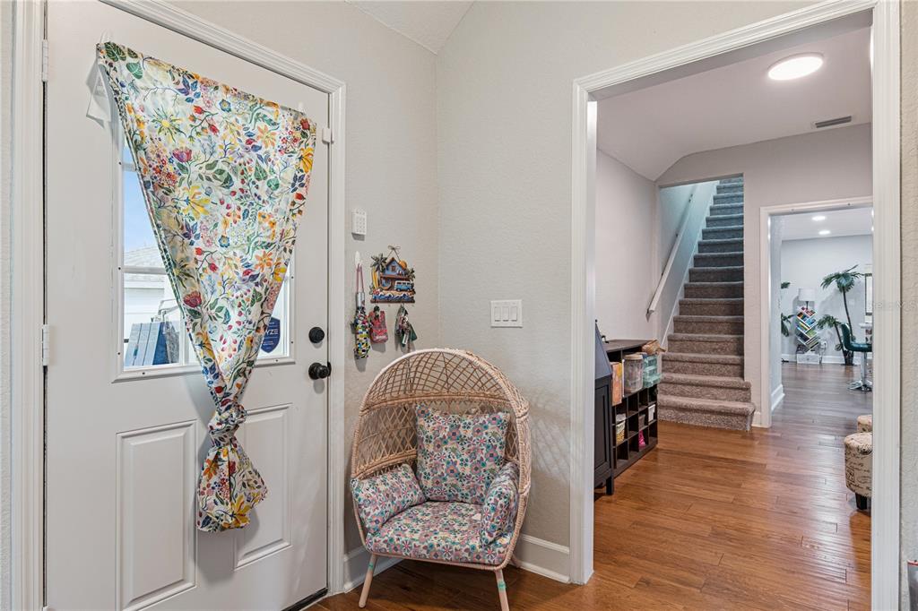 An entryway features a white door with a floral curtain, a wicker chair, and stairs — 732 E ORANGE AVENUE, EUSTIS, FL