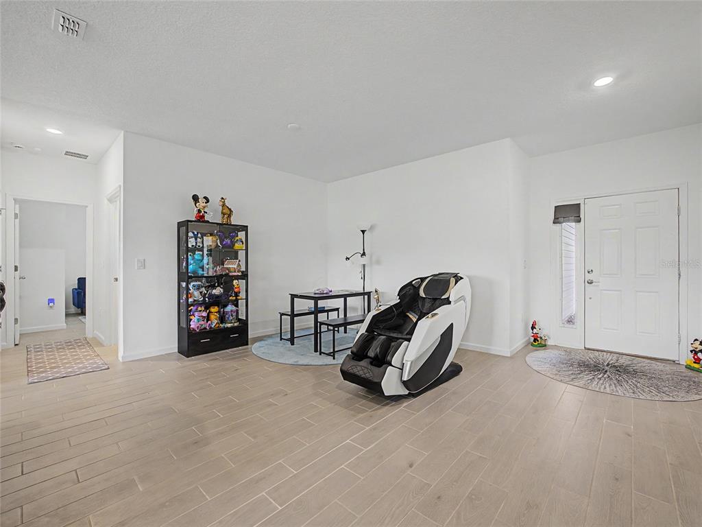 An aerial view of a single-story suburban house with a tan exterior and three-car garage — 7672 SW 74TH LOOP, OCALA, FL