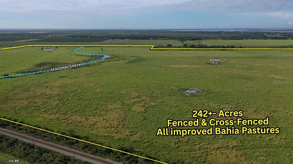 An aerial view shows a large, fenced pasture with several ponds and a seasonal creek — 4333 US-98, LORIDA, FL