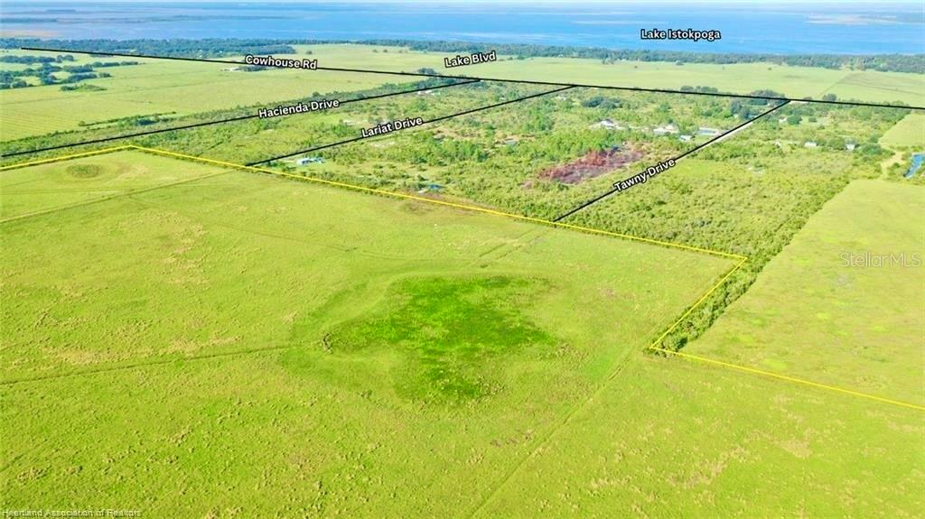 An aerial view shows a large, grassy field outlined in yellow near a lake — 4333 US-98, LORIDA, FL