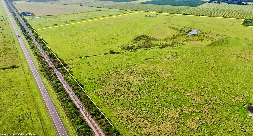 An aerial view shows a large, grassy field bordered by a highway and railroad tracks — 4333 US-98, LORIDA, FL