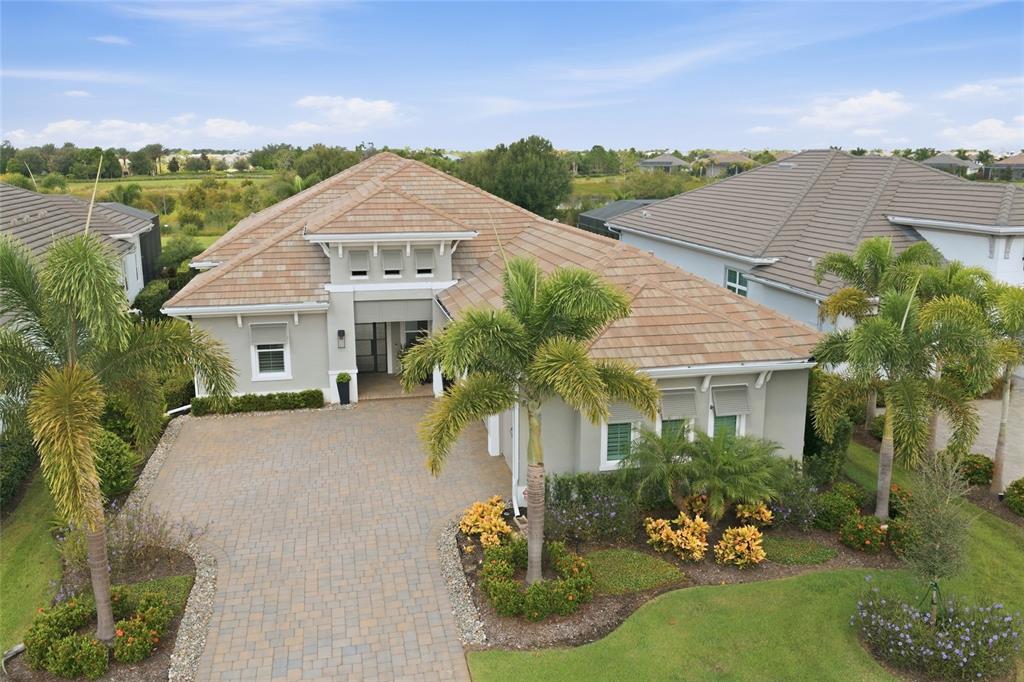 A bright open-concept living room features a coffered ceiling, fireplace, and sliding glass patio doors — 8254 PAVIA WAY, LAKEWOOD RANCH, FL