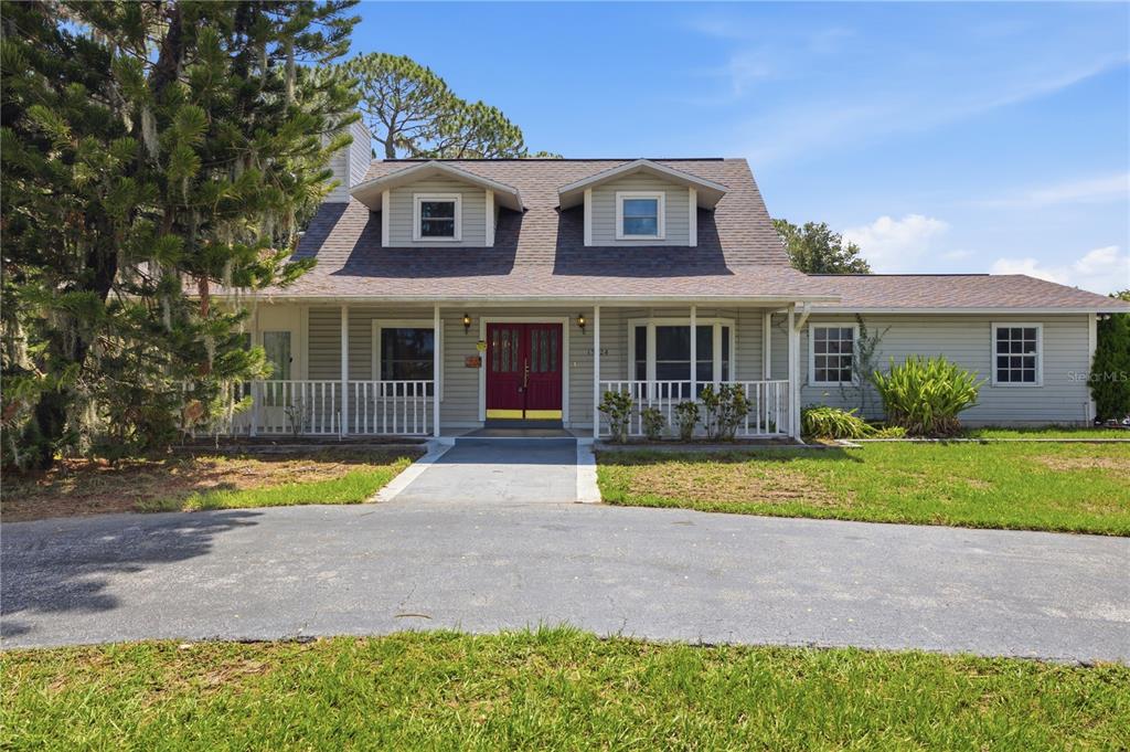 A two-story house with light siding, a red front door, and a covered porch — 15324 BALM WIMAUMA ROAD, WIMAUMA, FL