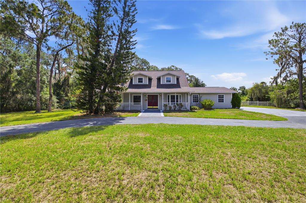 A two-story house with light siding, a front porch, and a circular driveway — 15324 BALM WIMAUMA ROAD, WIMAUMA, FL